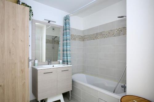 La salle de bains est pourvue d'une baignoire blanche, d'un lavabo et d'une baignoire. dans l'établissement T3 Panoramic view Toulouse, near Chu Rangueil, 2 chambres, tout équipé, neuf, à Toulouse