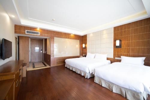 a hotel room with two beds and a television at Wanda Yue Hotel Changbaishan Chixi in Xinancha