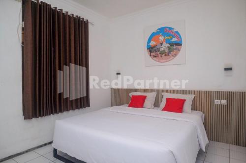 a bedroom with two beds with red pillows at Hotel Candra Kirana Syariah Prawirotaman Yogyakarta Mitra RedDoorz in Yogyakarta