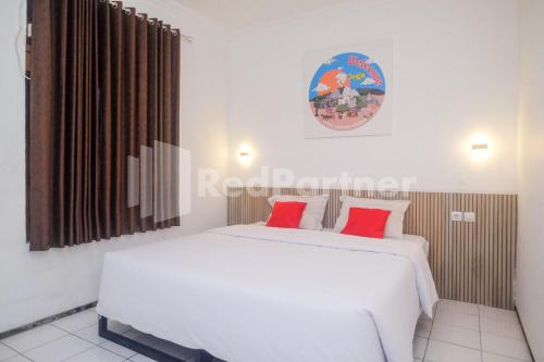 a bedroom with two beds with red pillows at Hotel Candra Kirana Syariah Prawirotaman Yogyakarta Mitra RedDoorz in Yogyakarta