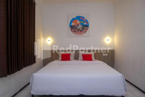 a bedroom with a large white bed with red pillows at Hotel Candra Kirana Syariah Prawirotaman Yogyakarta Mitra RedDoorz in Yogyakarta