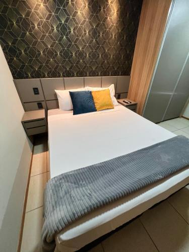 a bedroom with a white bed with two pillows at Apartamento de Luxo com Suíte, Academia, Piscina e Mercado in Cuiabá