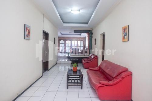 a living room with two red chairs and a table at Hotel Candra Kirana Syariah Prawirotaman Yogyakarta Mitra RedDoorz in Yogyakarta