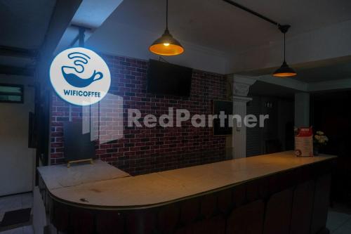 a bar with a red partner sign on a brick wall at Hotel Candra Kirana Syariah Prawirotaman Yogyakarta Mitra RedDoorz in Yogyakarta
