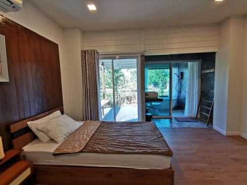 a bedroom with a bed and a sliding glass door at บ้านพระจันทร์เวียน - House of moon phase in Chachoengsao