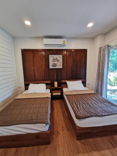 two beds in a room with wooden walls at บ้านพระจันทร์เวียน - House of moon phase in Chachoengsao