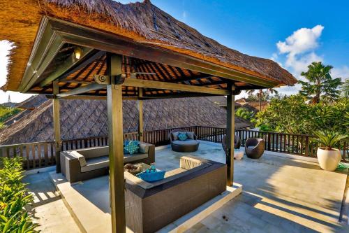 an outdoor patio with a thatched roof at The Residence Seminyak in Seminyak
