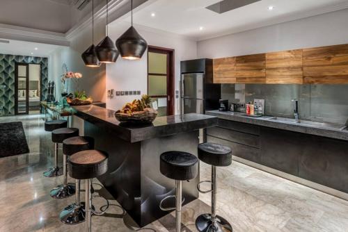 a kitchen with a large counter with stools in it at The Residence Seminyak in Seminyak