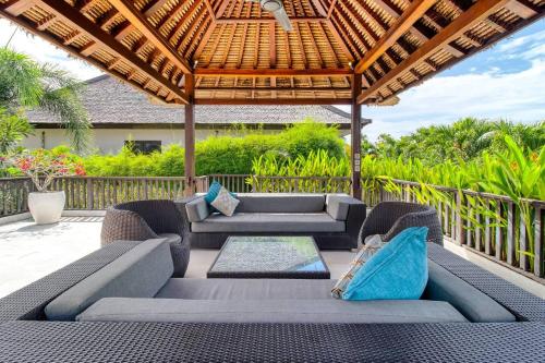 an outdoor patio with furniture and a pergola at The Residence Seminyak in Seminyak