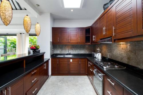 a kitchen with wooden cabinets and black counter tops at The Residence Seminyak in Seminyak