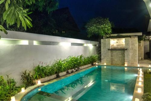 a swimming pool in a backyard at night at The Residence Seminyak in Seminyak