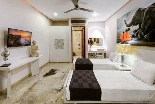 two beds in a room with paintings on the wall at The Residence Seminyak in Seminyak