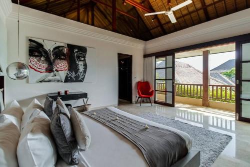 a bedroom with a large bed and a red chair at The Residence Seminyak in Seminyak