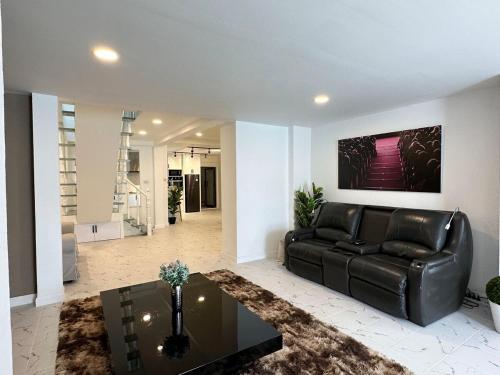 a living room with a black leather couch and a table at G Cozy Pool Villa in Pattaya South