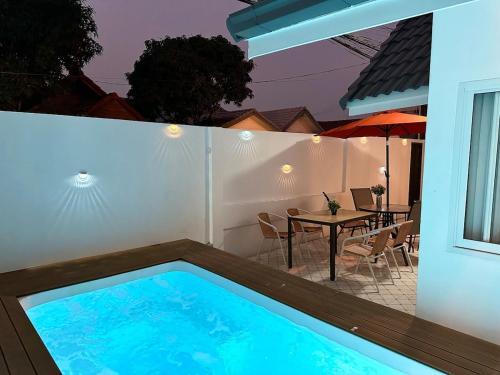 a swimming pool in a backyard with a table and umbrella at G Cozy Pool Villa in Pattaya South