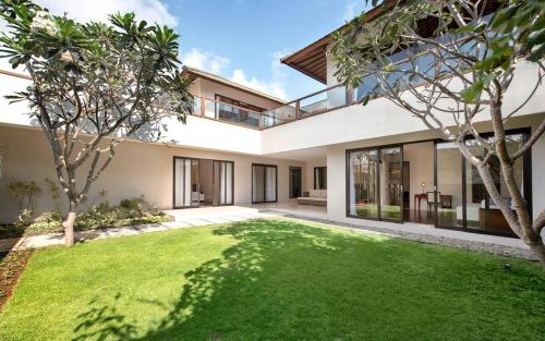an open courtyard of a house with a green lawn at Karang Saujana in Uluwatu