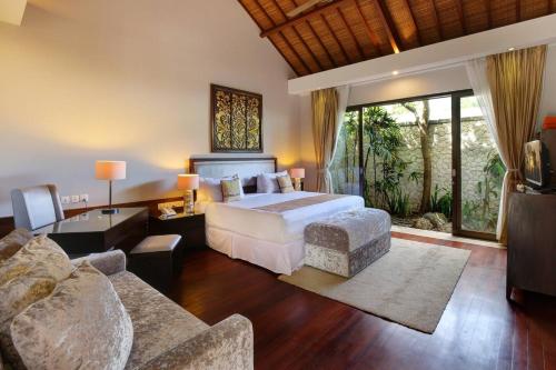 a bedroom with a bed and a living room at Karang Saujana in Uluwatu