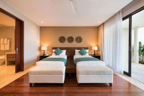 a bedroom with four beds and two chairs at Karang Saujana in Uluwatu