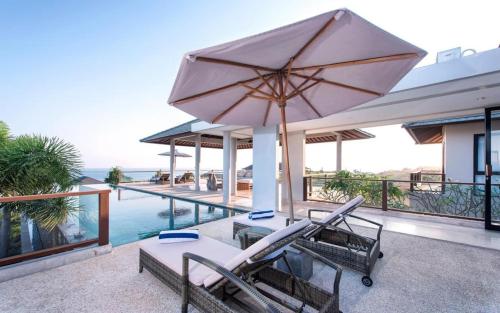 a patio with a table and chairs and an umbrella at Karang Saujana in Uluwatu