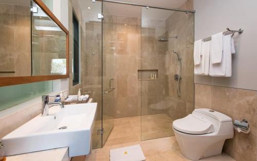 a bathroom with a shower and a toilet and a sink at Karang Saujana in Uluwatu