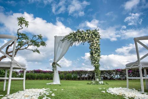 a wedding aisle with two white chairs and a white canopy at Karang Saujana in Uluwatu