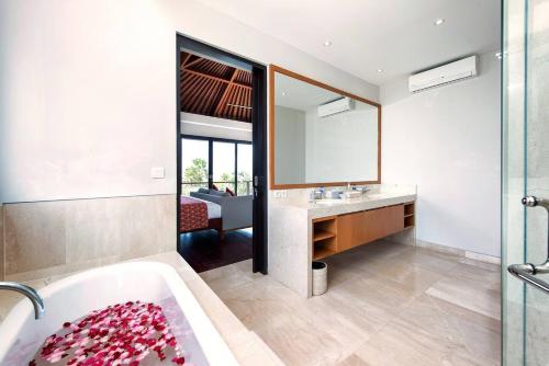 a bathroom with a tub and a sink and a mirror at Karang Saujana in Uluwatu