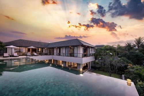 a villa with a swimming pool at sunset at Karang Saujana in Uluwatu
