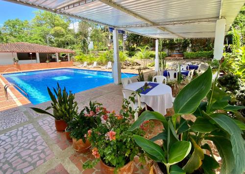 un patio con piscina, mesas y plantas en Hotel Davilejas, en San Gil