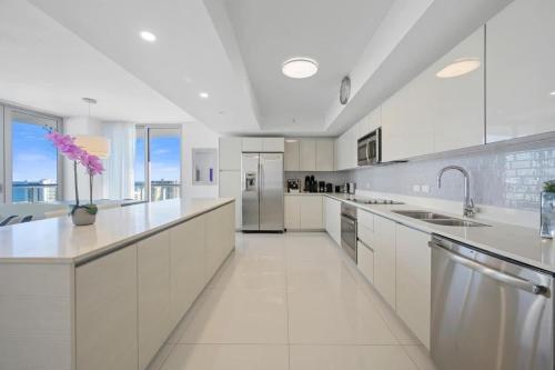una gran cocina blanca con armarios y electrodomésticos blancos en Luxury 3BR With Stunning Views on High Floor, en Hallandale Beach