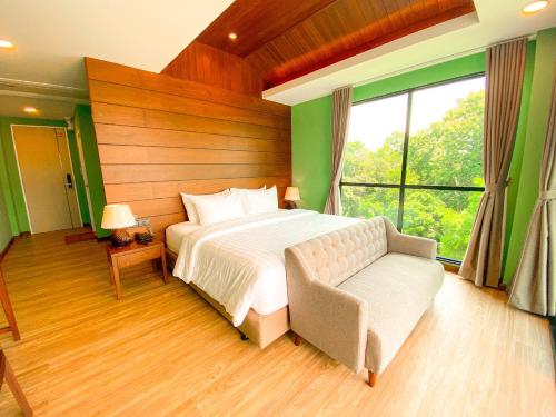 a bedroom with a bed and a couch and a window at River Tree Resort in Chiang Khan