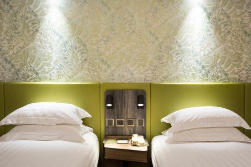 two beds in a room with a green wall at Wharney Hotel in Hong Kong