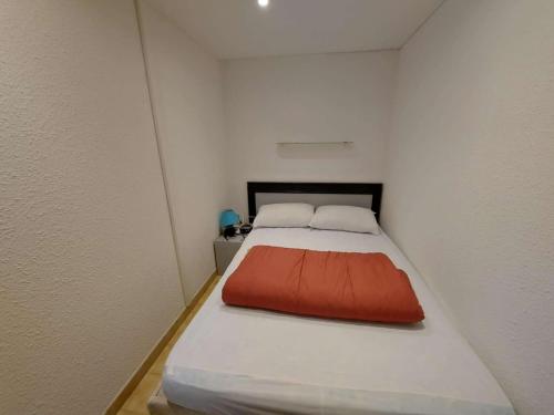 Cette petite chambre comprend un lit avec un oreiller orange. dans l'établissement Confort et espace : Apt 2P mezzanine avec parking à Marseillan - FR-1-326-840, à Marseillan