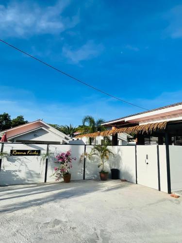 a white fence in front of a house with plants at Rooma Kichi Private Pool in Pantai Cenang