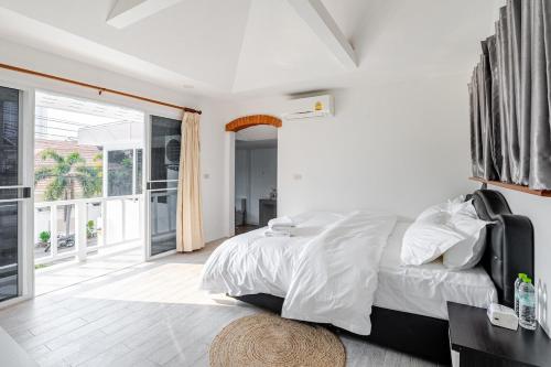 a white bedroom with a bed and a balcony at G warmth Pool Villa in Pattaya South