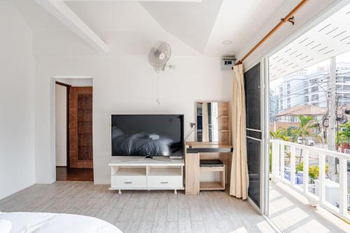 a bedroom with a large television and a balcony at G warmth Pool Villa in Pattaya South