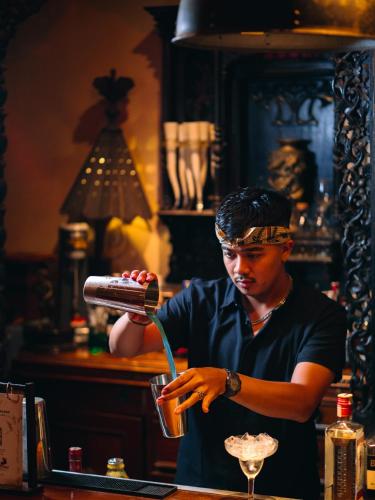 a man standing at a bar making a drink at Hotel Tugu Malang in Malang