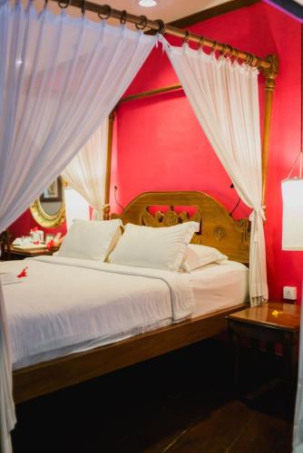 a bedroom with a large bed with a red wall at Hotel Tugu Malang in Malang