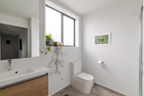 Un baño blanco con inodoro y lavabo. en 2024 Townhouse, en Christchurch
