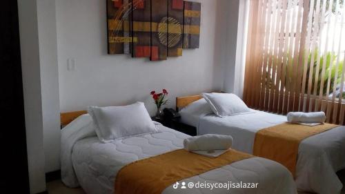 a room with two beds and a painting on the wall at Hotel Cristal Plaza in Popayan