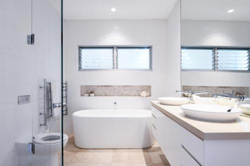a white bathroom with two sinks and a tub at Warriewood beach house in Mona Vale