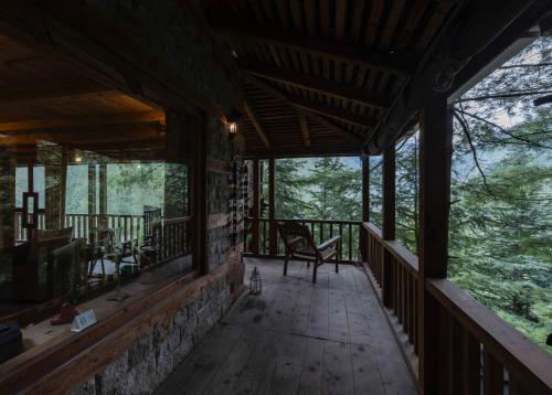 a screened in porch of a cabin in the woods at Kudrat - A Boutique Homestay- Tirthan Valley in Banjār