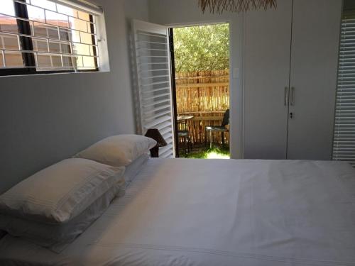 a bedroom with two beds and a view of a patio at Happy's Hood in Pringle Bay