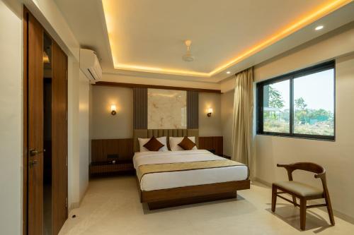 a bedroom with a bed and a chair and a window at Diora Inn in Pune