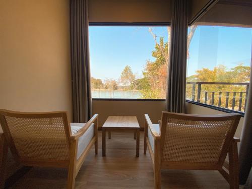 a room with two chairs and a table and a large window at River Tree Resort in Chiang Khan