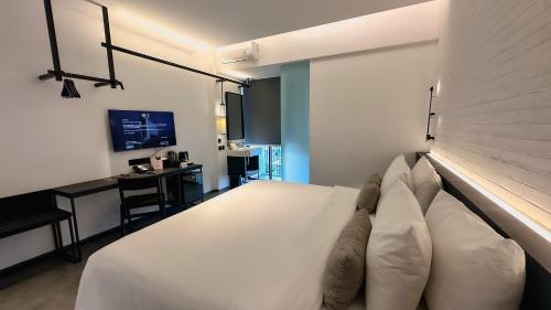 a bedroom with a large white bed with a desk at REZ Hotel in Semarang