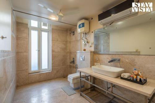 a bathroom with a sink and a toilet and a mirror at StayVista at Abode Aurum with WiFi in Gurgaon