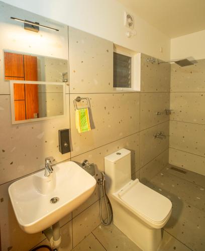 a bathroom with a white toilet and a sink at Hotel Eden Palace in Trichūr