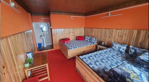 two beds in a room with orange walls at Nivvana Homestay By StayApart in Lava