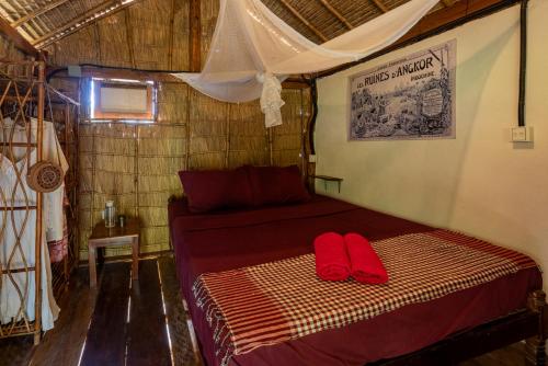 a bed in a room with two red pillows on it at Kampot Cabana in Kampot