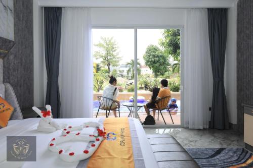 a hotel room with a bed with people sitting in chairs at Premium CGP Hotel Hoi An in Hoi An